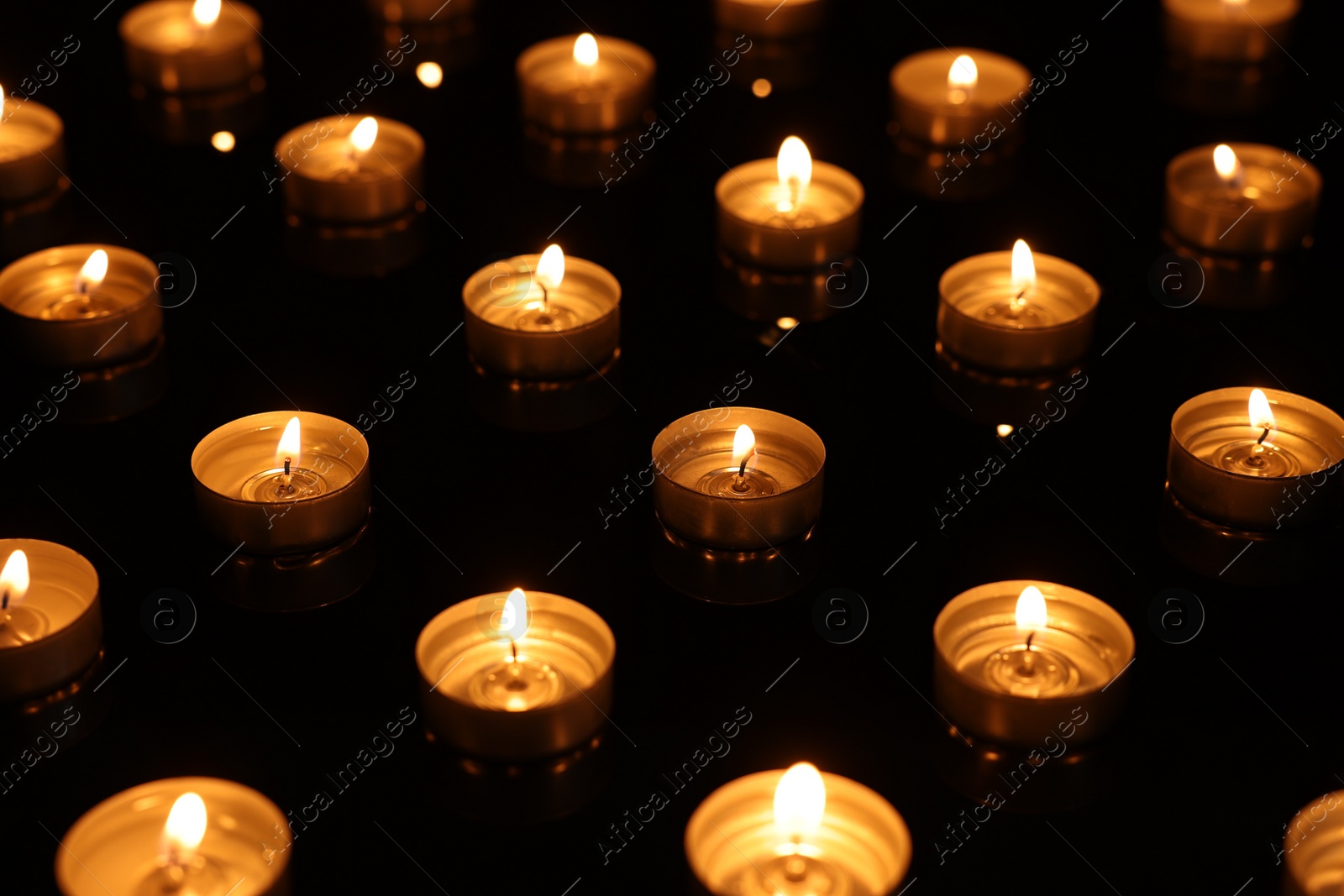 Photo of Burning candles on mirror surface in darkness