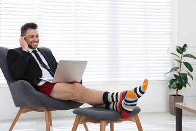 Businessman in underwear pretending to wear formal clothes during video call at home