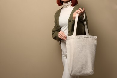 Woman with eco bag on beige background, closeup. Space for text