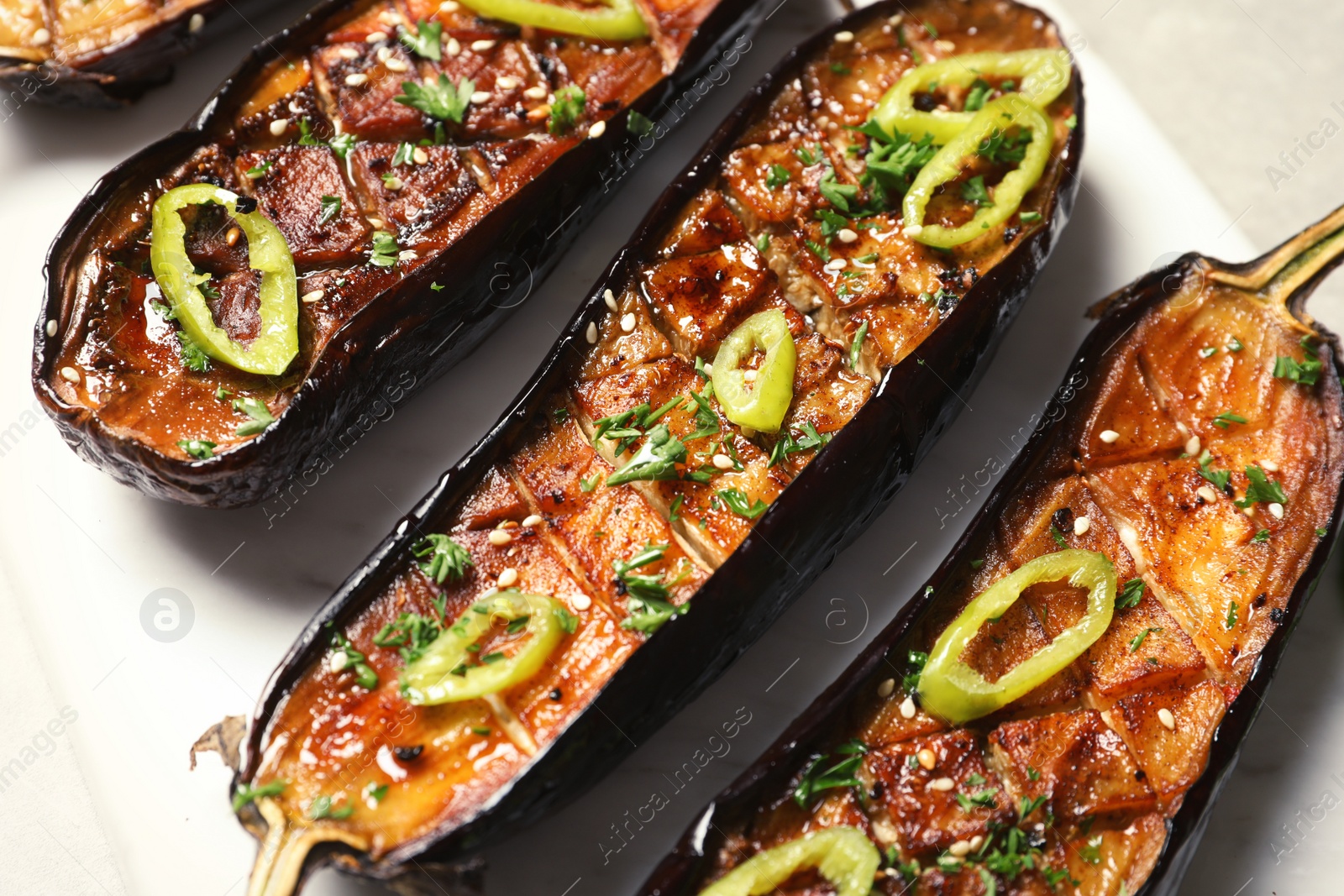 Photo of Fried eggplant slices with chili peppers on light background, closeup