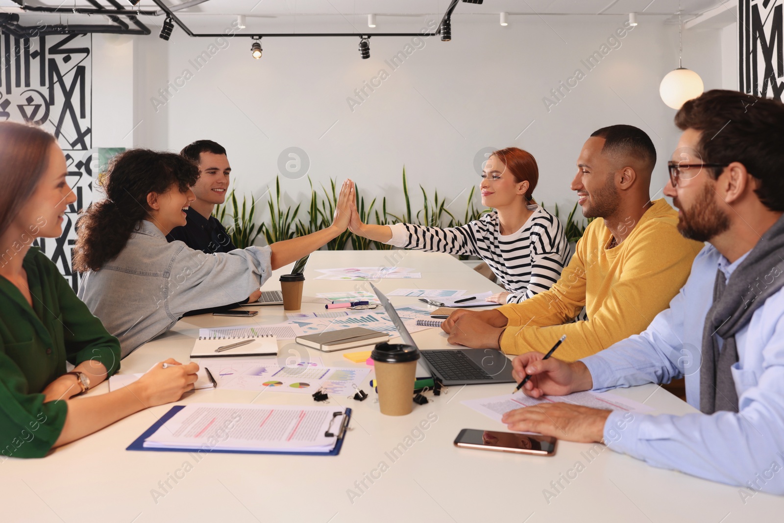 Photo of Team of employees working together at table in office. Startup project