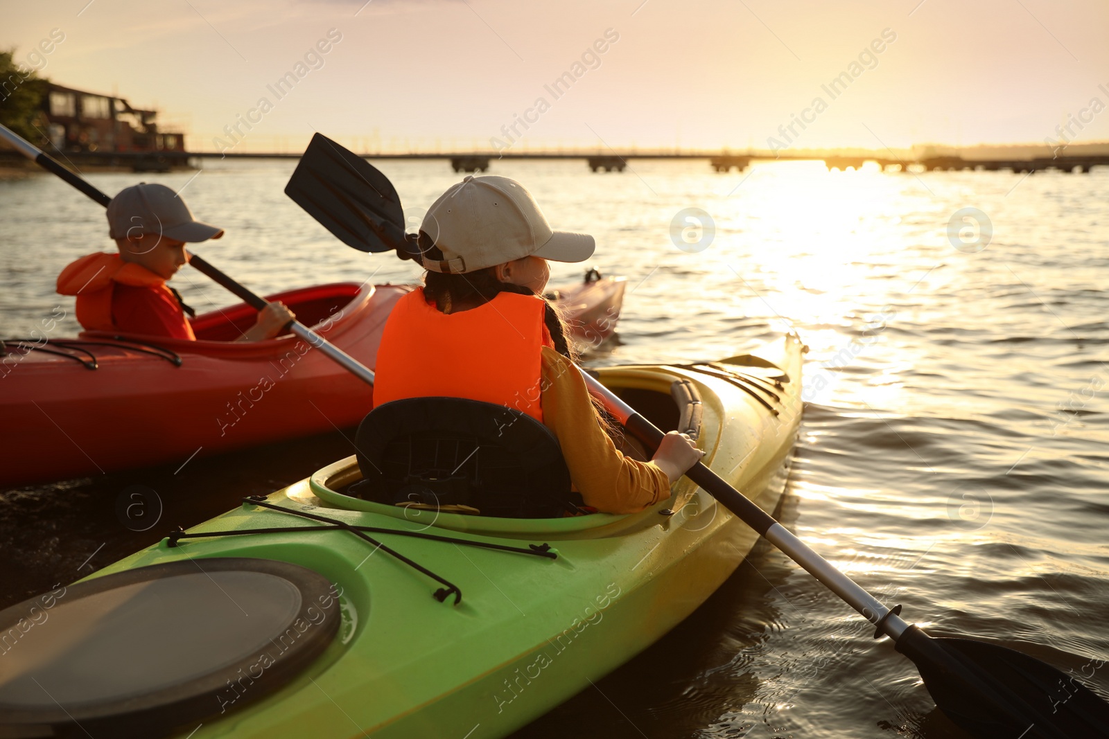 Photo of Little children kayaking on river, back view. Summer camp activity