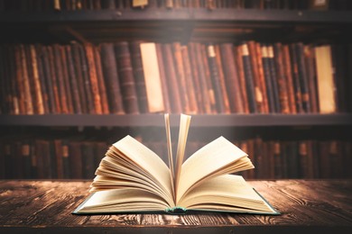 Open book on wooden table in library