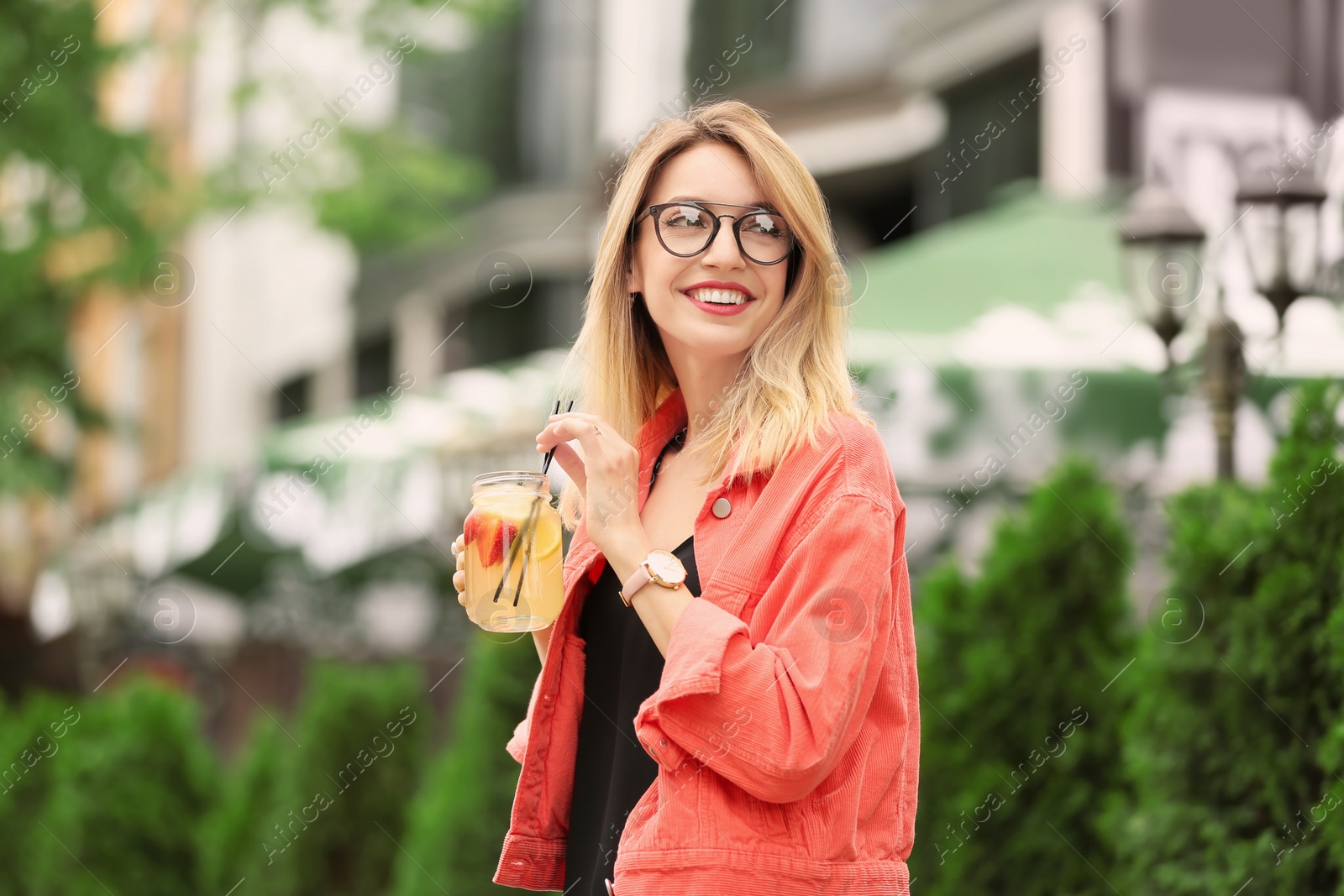 Photo of Young woman with mason jar of tasty lemonade outdoors