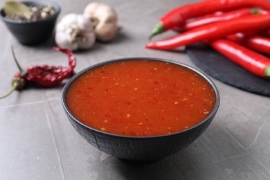 Photo of Spicy chili sauce in bowl on grey table