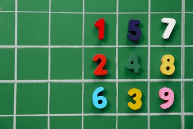 Many colorful numbers on green chalkboard, flat lay