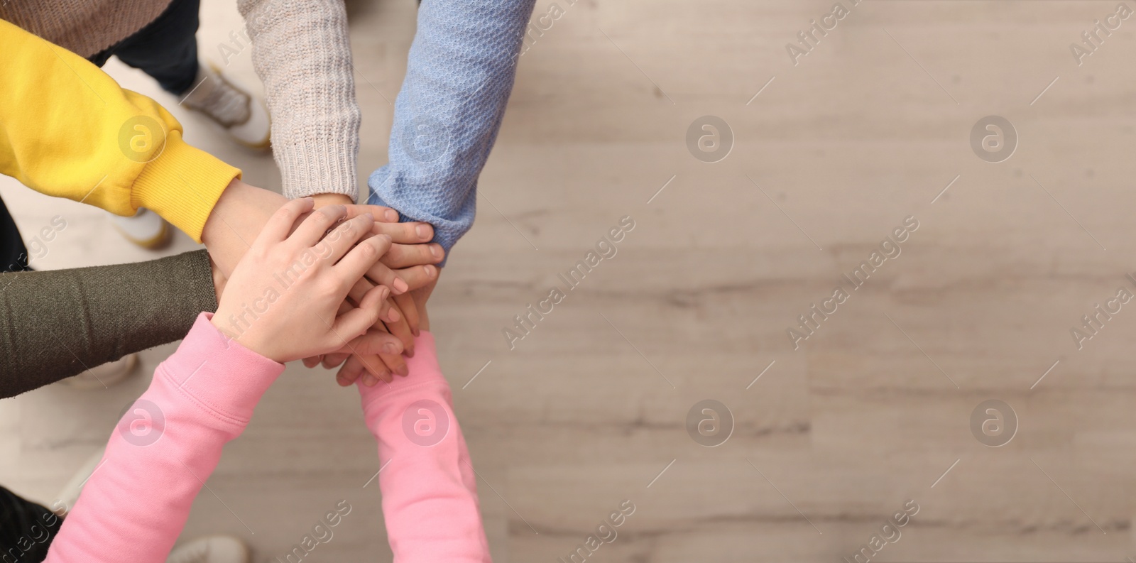 Photo of Group of people holding their hands together indoors, top view. Space for text