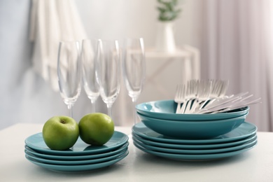 Photo of Set of clean dishware, cutlery and champagne glasses on white table indoors