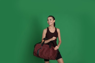 Beautiful woman with sports bag on green background