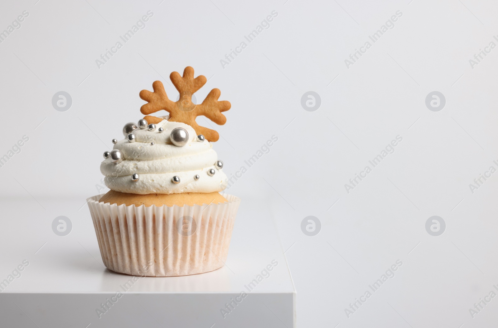 Photo of Tasty Christmas cupcake with cream and snowflake cookie on white table, space for text