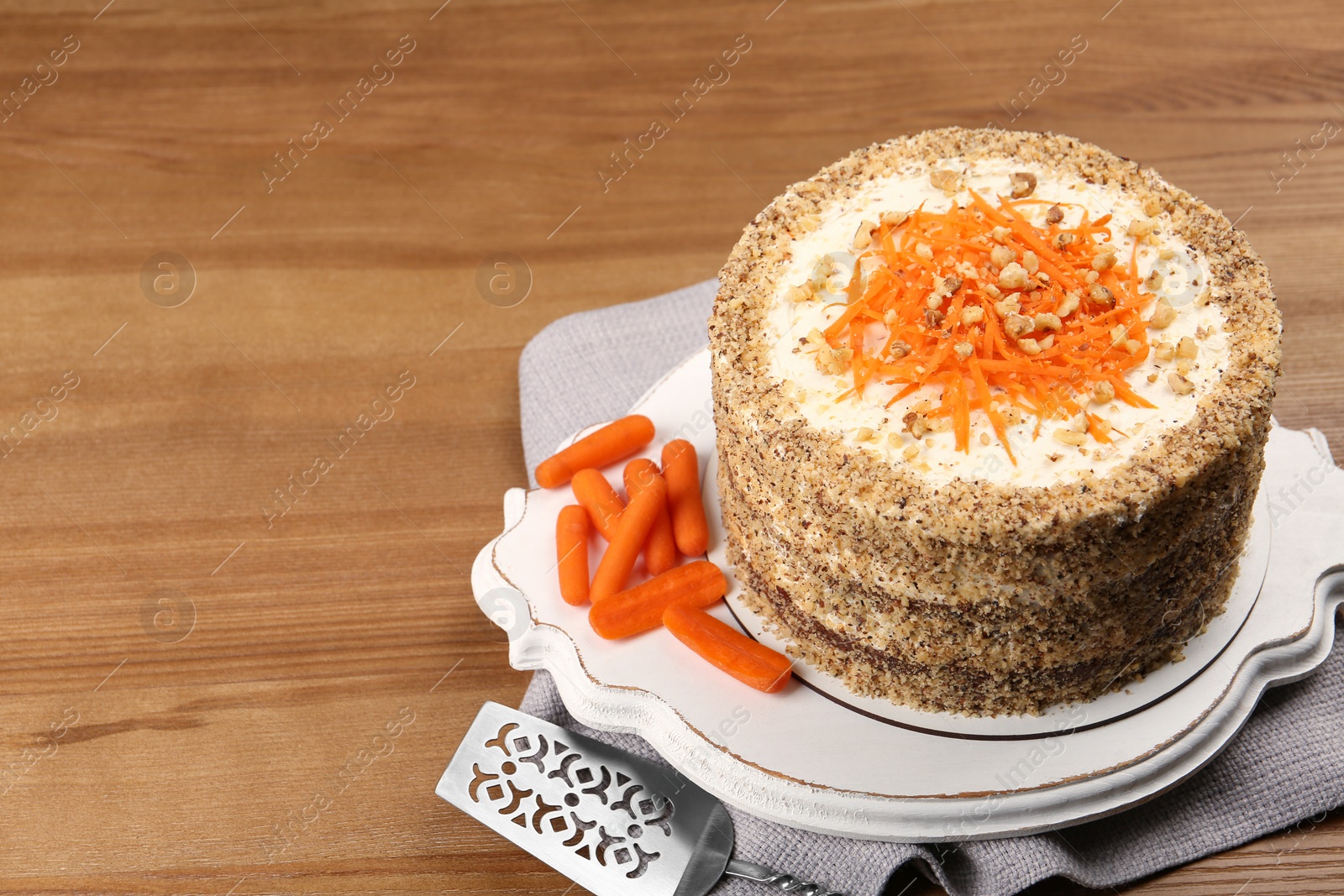 Photo of Sweet carrot cake with delicious cream on wooden table, space for text