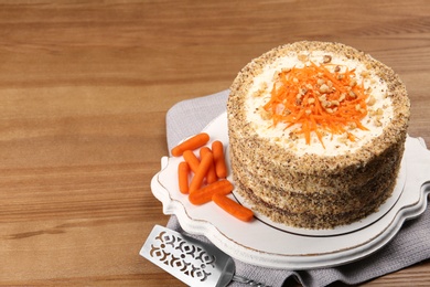 Photo of Sweet carrot cake with delicious cream on wooden table, space for text