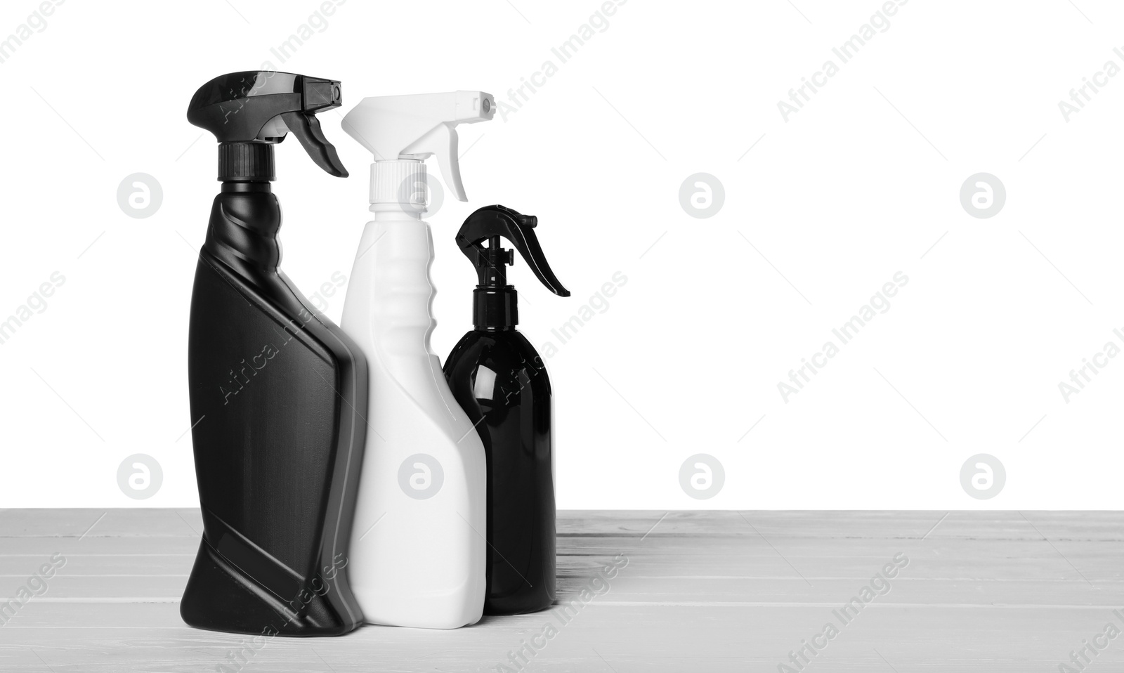 Photo of Different spray bottle on wooden table against white background