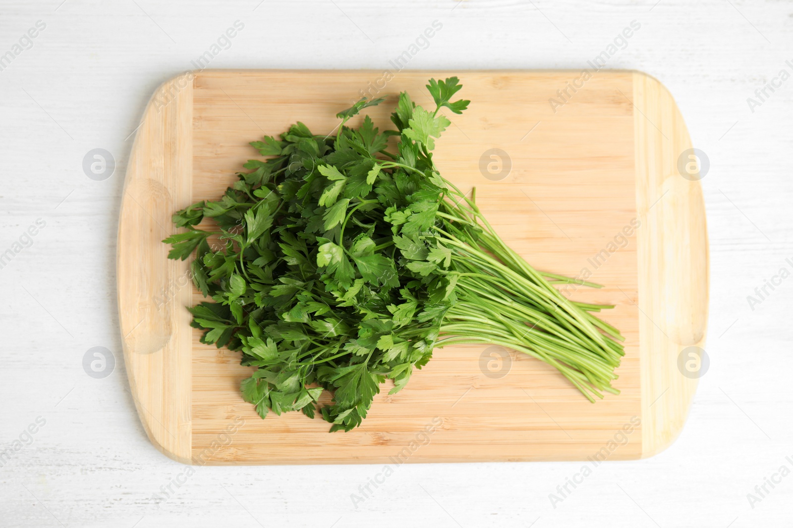 Photo of Board with fresh green parsley on wooden background, top view