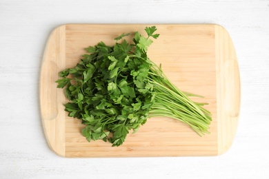 Board with fresh green parsley on wooden background, top view