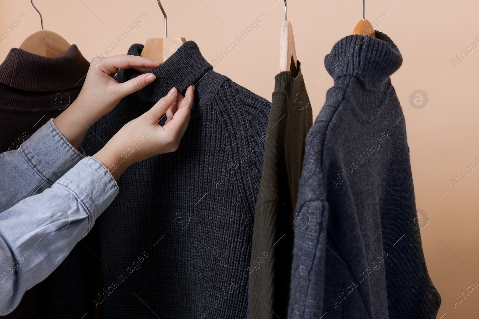 Photo of Woman taking casual sweater on beige background, closeup