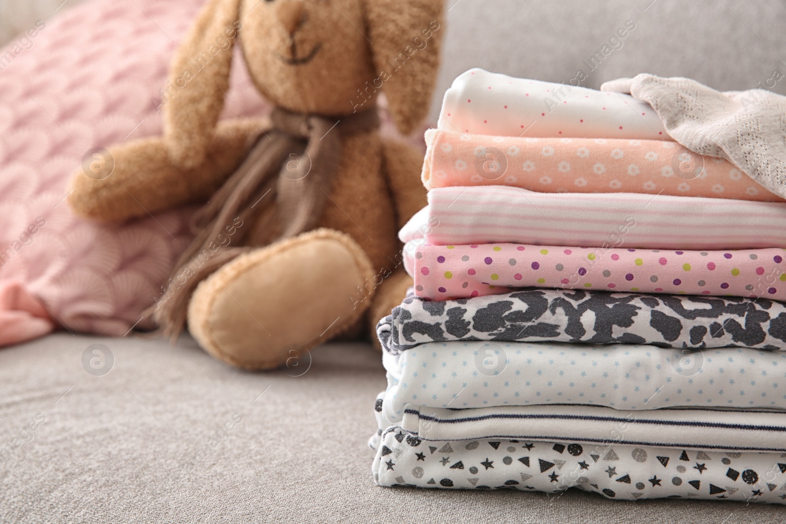 Photo of Stack of stylish child clothes on sofa