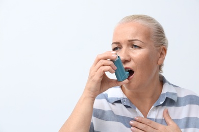 Photo of Woman using asthma inhaler on white background