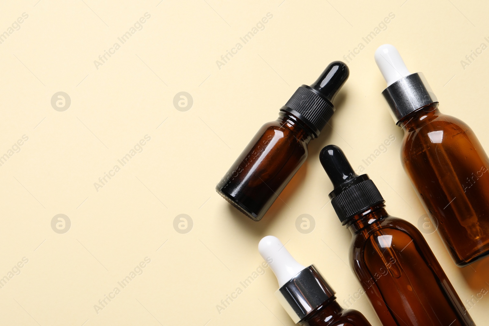 Photo of Many bottles with face serums on beige background, flat lay. Space for text