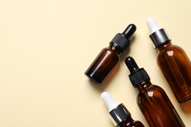 Photo of Many bottles with face serums on beige background, flat lay. Space for text