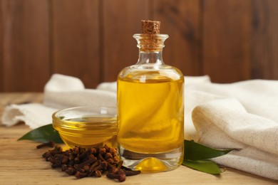 Photo of Essential oil and dried cloves on wooden table