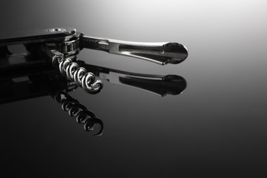 Photo of One corkscrew (sommelier knife) on mirror surface, closeup