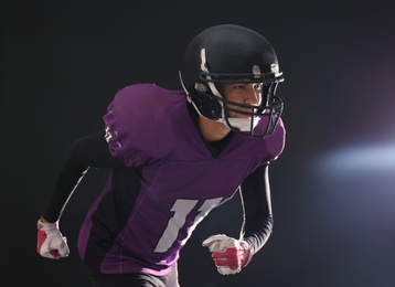 Photo of American football player wearing uniform on dark background