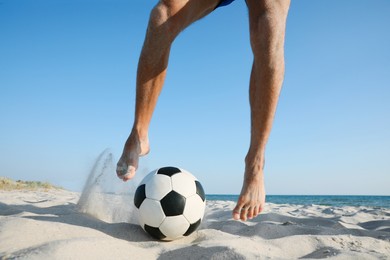 Photo of Man playing football on beach, closeup view