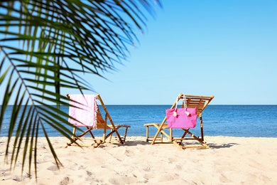 Photo of Empty wooden sunbeds and beach accessories on sandy shore