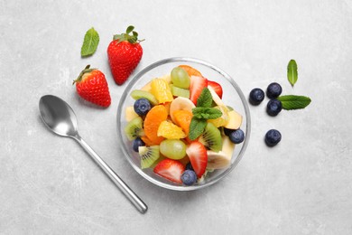 Photo of Delicious fresh fruit salad in bowl on light table, flat lay