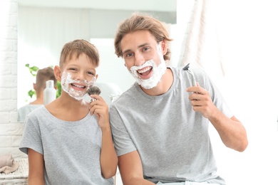 Father and son shaving together in bathroom