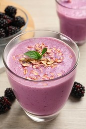 Photo of Delicious blackberry smoothie with oatmeal in glass on white wooden table, closeup