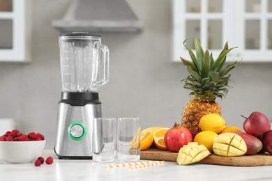 Photo of Blender and smoothie ingredients on white marble table in kitchen