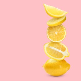 Image of Stacked cut and whole lemons on pale pink background, space for text