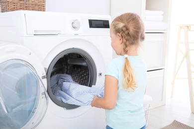 Photo of Adorable little girl doing laundry at home