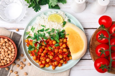 Photo of Delicious chickpea curry with rice served on white wooden table, flat lay