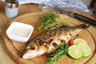 Photo of Delicious grilled fish served on wooden table