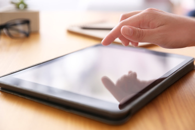 Photo of Woman working with modern tablet at wooden table, closeup