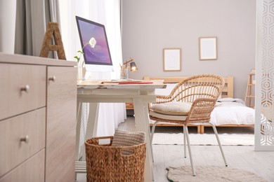 Photo of Comfortable workplace with modern computer near window in bedroom. Interior design