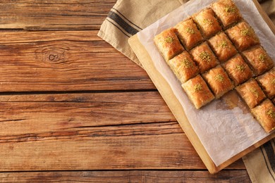 Photo of Delicious sweet baklava on wooden table, top view. Space for text