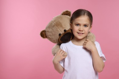 Photo of Cute girl with teddy bear on pink background, space for text
