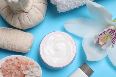 Photo of Beautiful composition with spa products and flowers on light blue background, flat lay