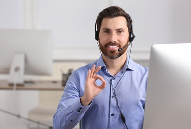 Photo of Hotline operator with headset showing OK gesture in office, space for text