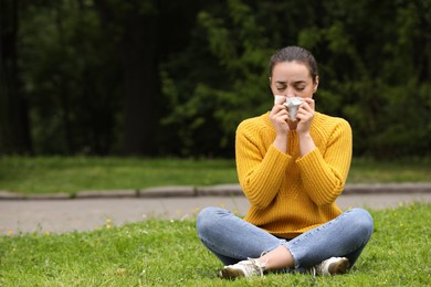 Photo of Woman suffering from seasonal spring allergy on green grass in park. Space for text