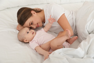 Photo of Portrait of mother with her cute baby lying on bed