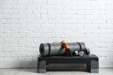 Photo of Set of fitness inventory on floor near brick wall. Space for text