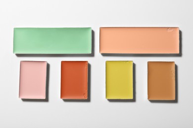 Photo of Different color correcting concealers on white background, top view