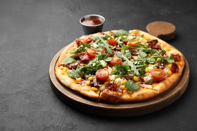 Photo of Delicious vegetarian pizza with cheese, mushrooms, vegetables and greens on black table