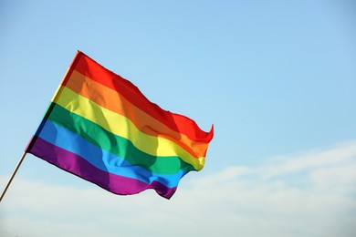Photo of Bright LGBT flag against blue sky with clouds, space for text