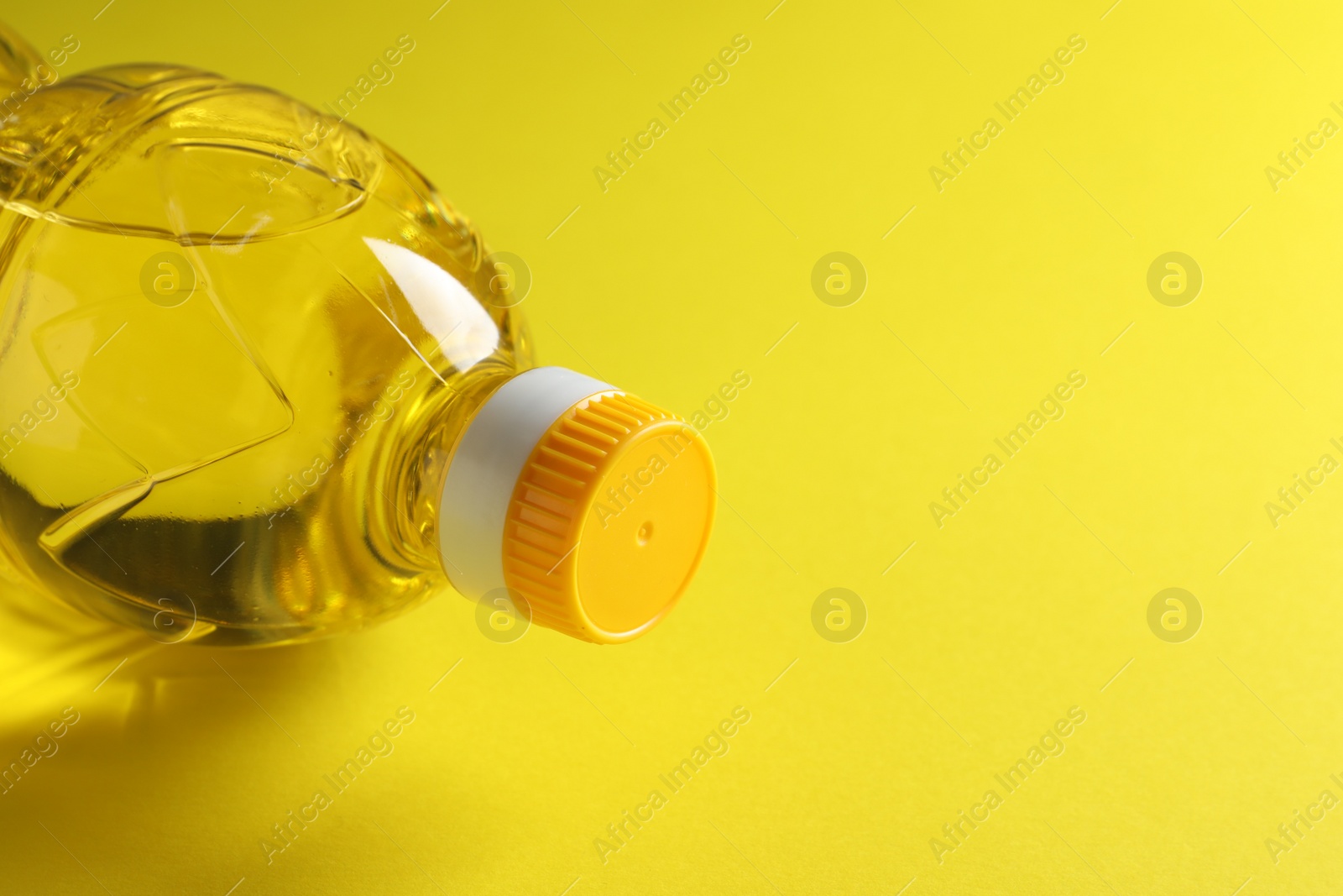 Plastic bottle of cooking oil on yellow background. Space for text Photo of Plastic bottle of cooking oil on yellow background. Space for text